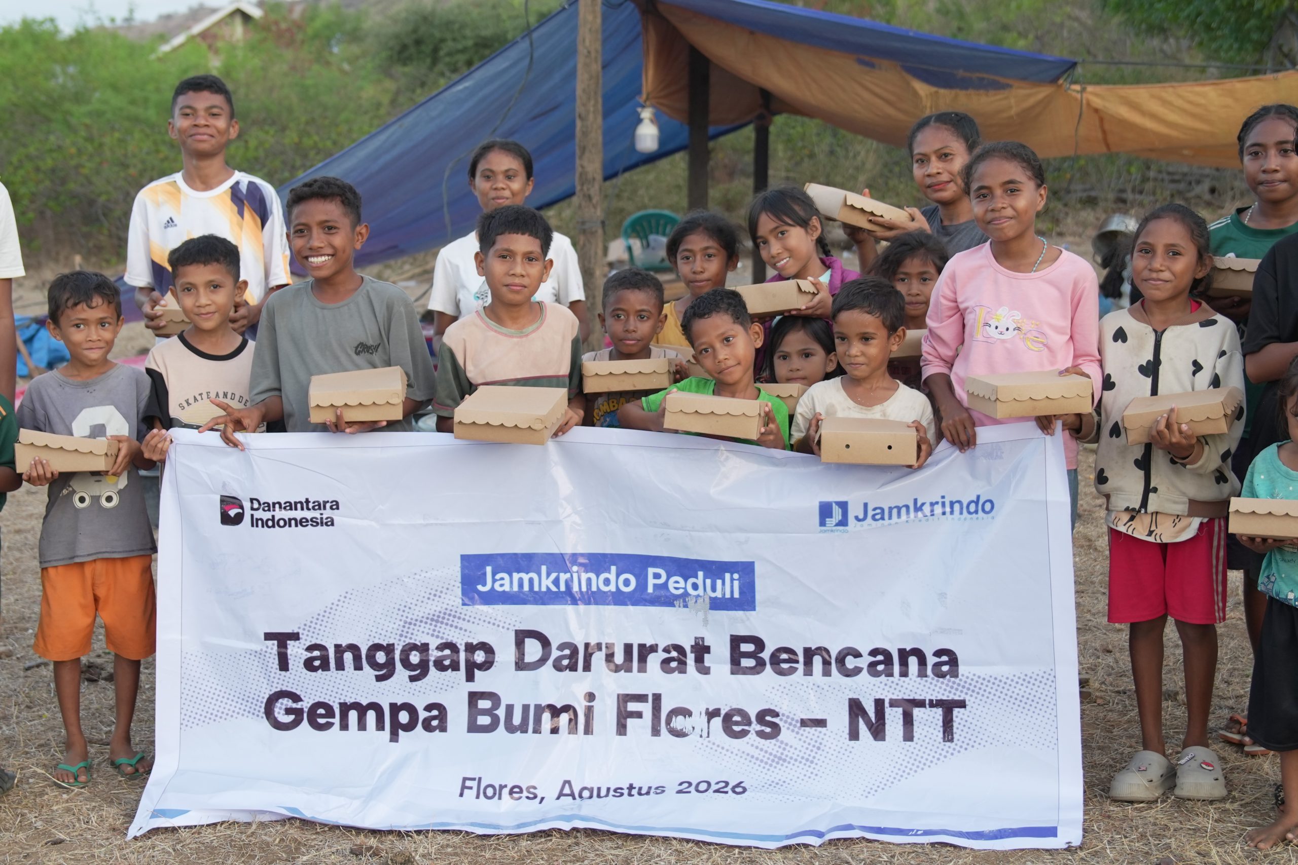 bantuan-makanan-siap-saji-gempa-flores-relawan-nusantara-jamkrindo Penyintas gempa Flores di Nagekeo foto bersama membawa paket makanan siap saji dengan spanduk Jamkrindo Peduli dan Relawan Nusantara.