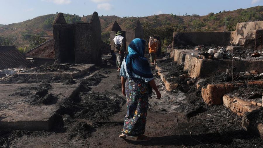 kebakaran-desa-adat-sade-lombok-tengah-04-puing-udara-Foto=Reuterscnbcindonesia Warga melintasi reruntuhan gerbang dan bangunan adat Desa Sade pascakebakaran di Lombok Tengah, NTB
