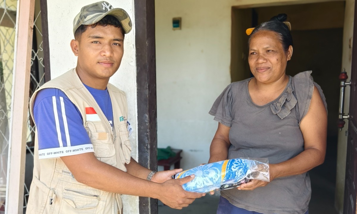 penyaluran-bantuan-selimut-penyintas-bencana Relawan menyerahkan bantuan selimut dan pakaian kepada seorang ibu penyintas bencana.