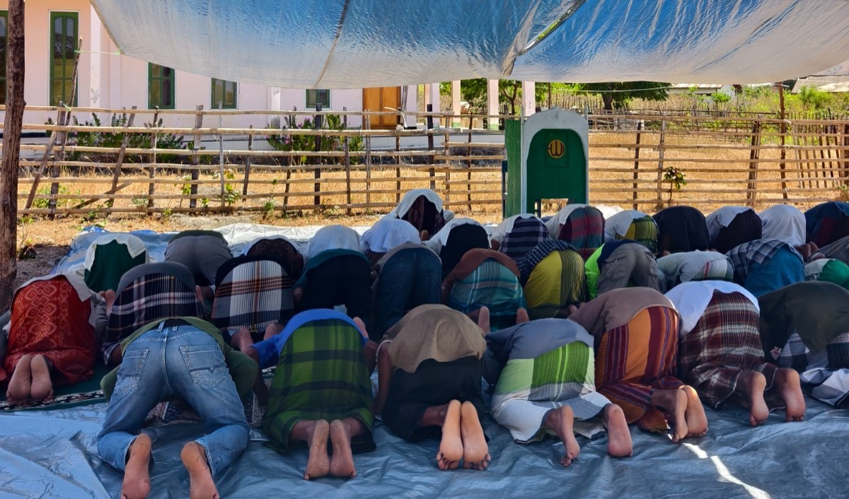 Deretan warga Waekokak sedang bersujud dengan khusyuk saat shalat di mushola darurat beralaskan terpal tipis.