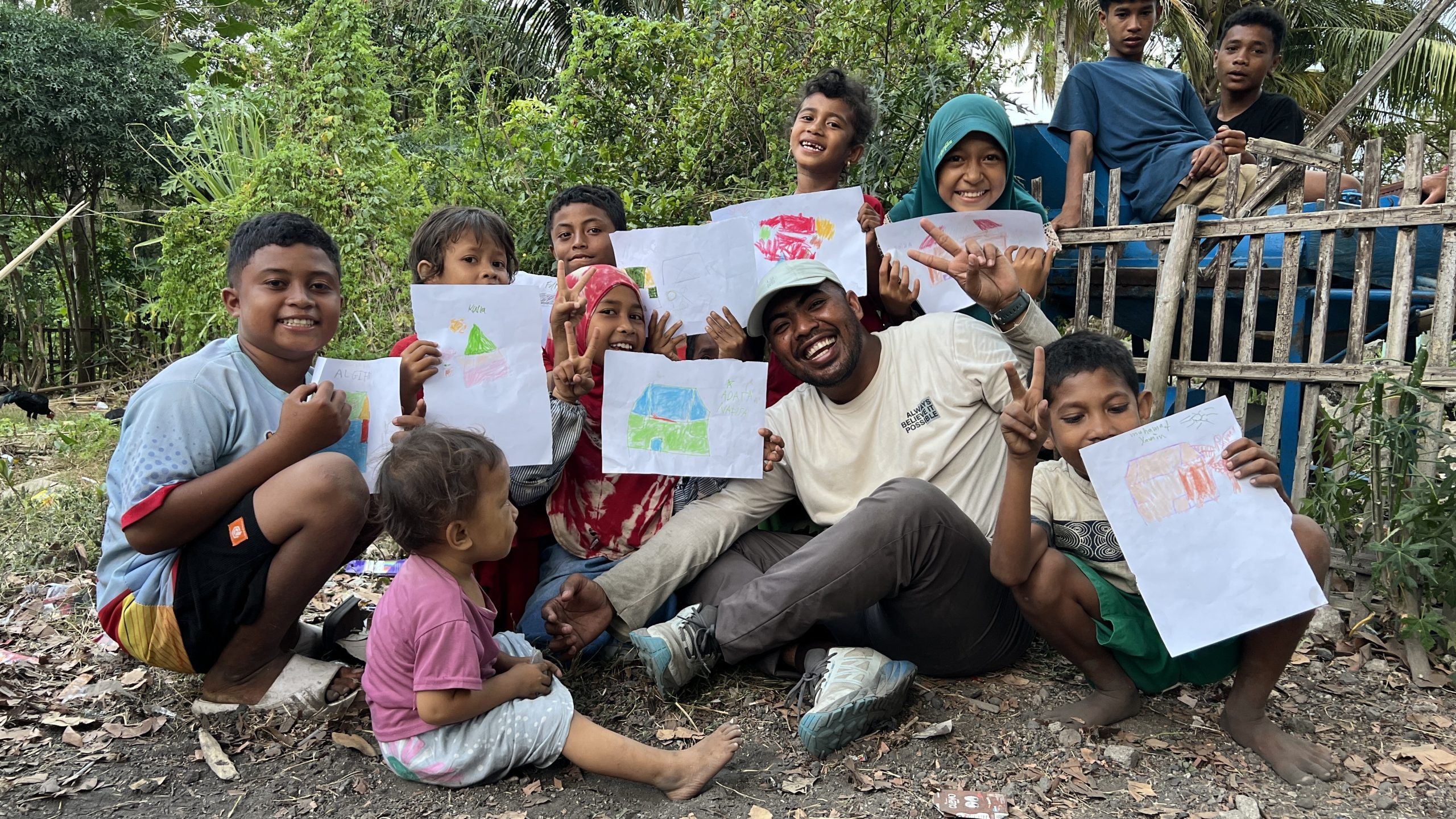 keceriaan-anak-anak-bersama-relawan-nusantara-desa-haju-wangi Momen kebersamaan relawan dan anak-anak desa yang memegang hasil karya mewarnai dalam program dukungan psikososial Relawan Nusantara.
