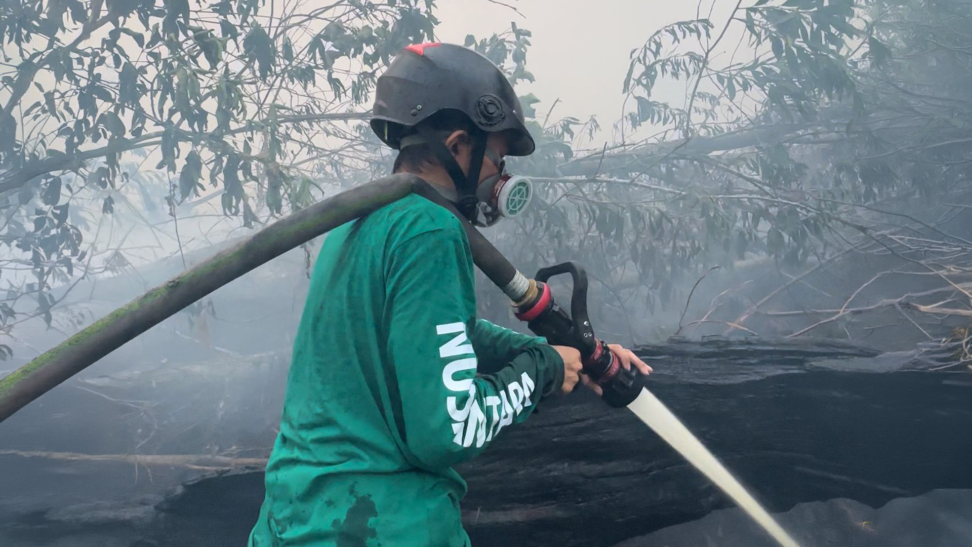 kolaborasi-relawan-nusantara-dan-damkar-karhutla Anggota Relawan Nusantara bersama petugas Damkar bahu-membahu membawa selang di lokasi pemadaman kebakaran lahan.