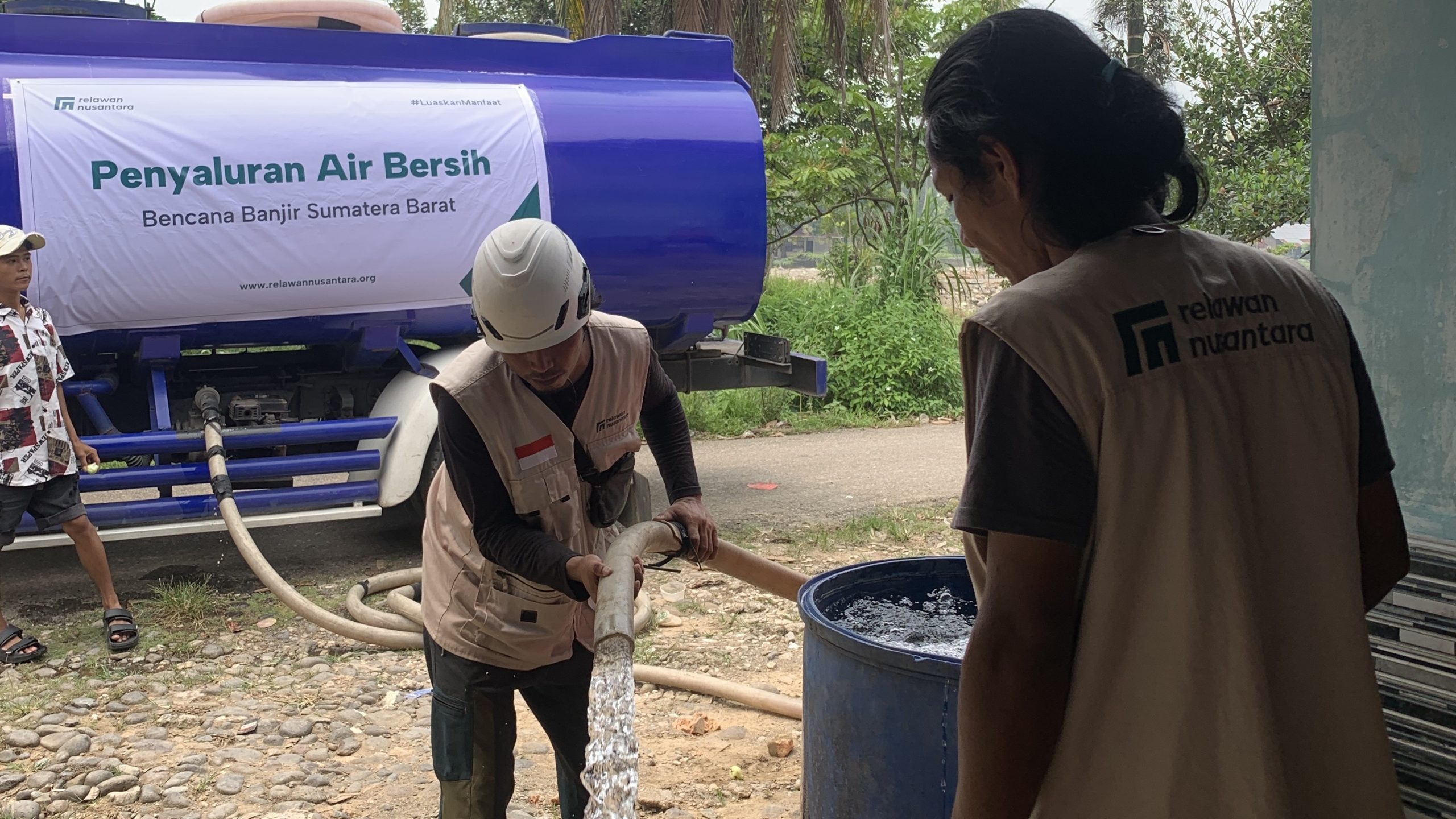Petugas Relawan Nusantara mengisi drum penampungan air bersih warga menggunakan selang dari truk tangki di Padang.